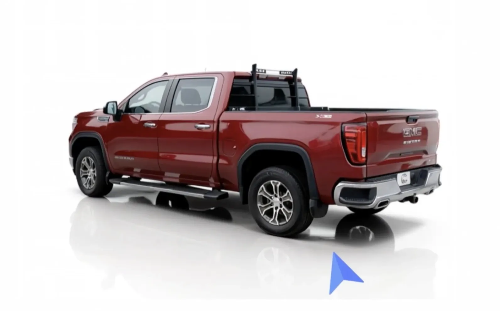 A red GMC Sierra pickup truck with a double cab and rugged tires, viewed from the rear side against a white background.
