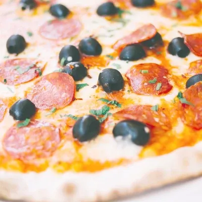Washed-out photo of a pepperoni and olive pizza, before relighting