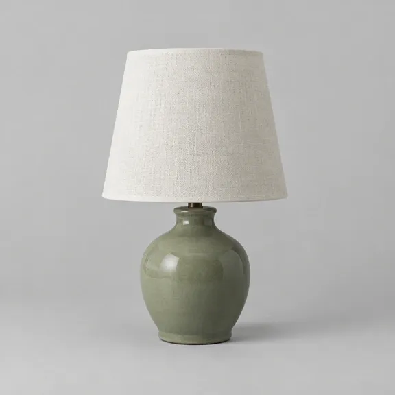 The same sage green ceramic table lamp relit by the Photoroom API with bright, even light